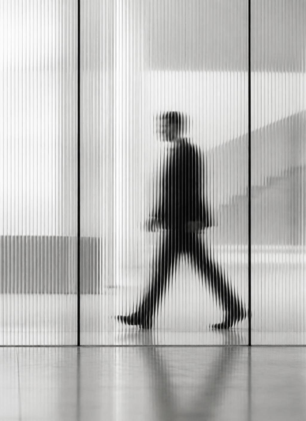 A blurred figure walking behind ribbed glass